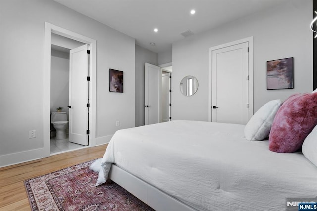 bedroom featuring recessed lighting, wood finished floors, baseboards, and ensuite bathroom