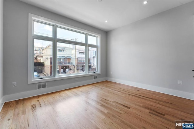 unfurnished room with visible vents, baseboards, and wood finished floors