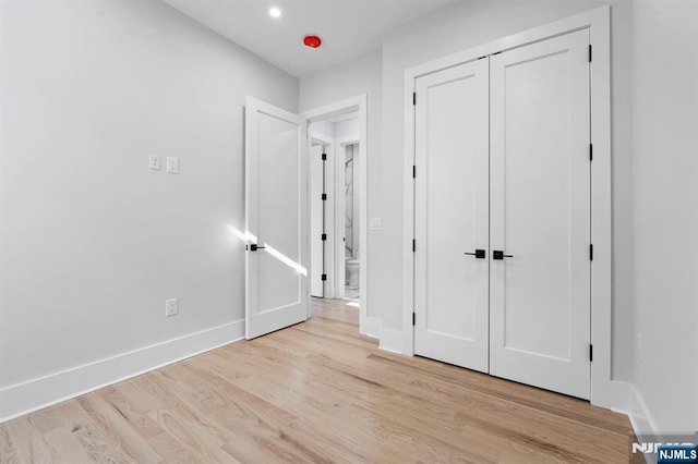 unfurnished bedroom featuring recessed lighting, baseboards, light wood-type flooring, and a closet