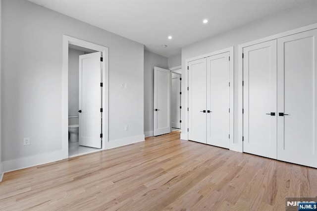 unfurnished bedroom featuring light wood-style flooring, recessed lighting, baseboards, and two closets