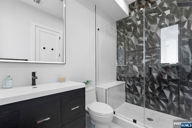 bathroom featuring visible vents, a stall shower, toilet, and vanity