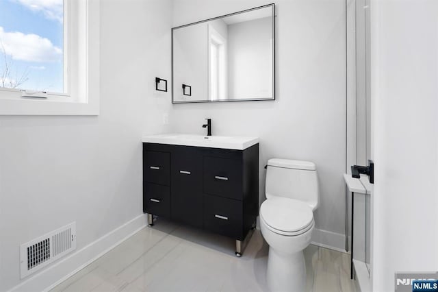 bathroom featuring visible vents, baseboards, toilet, and vanity