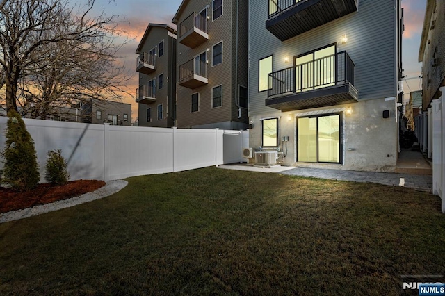 exterior space with a patio, a balcony, a yard, a fenced backyard, and central air condition unit