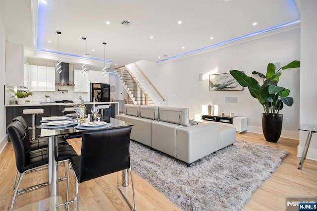 living area featuring stairway, recessed lighting, light wood-style floors, and ornamental molding