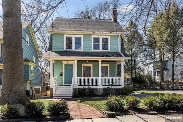 traditional style home with a porch, fence, and a chimney