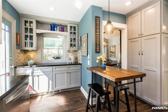 kitchen featuring dark countertops, glass insert cabinets, tasteful backsplash, and wood finish floors