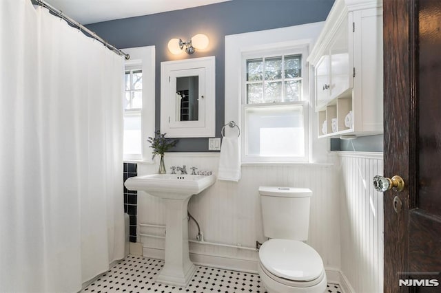 bathroom with a sink, toilet, and wainscoting