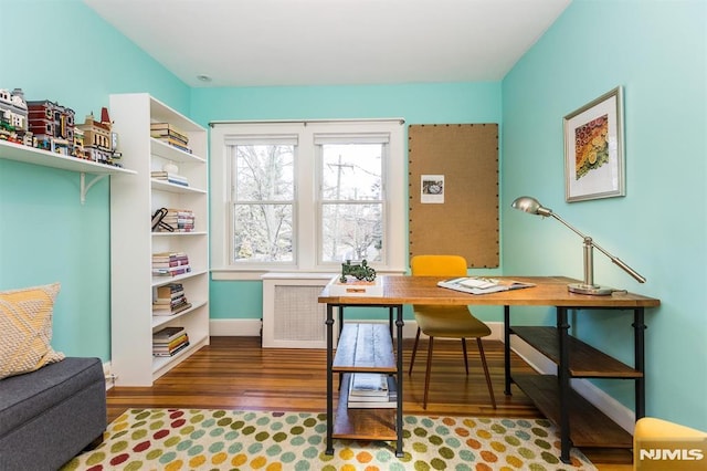 home office with radiator heating unit, baseboards, and wood finished floors