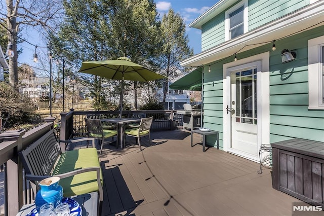 wooden terrace featuring area for grilling and outdoor dining area