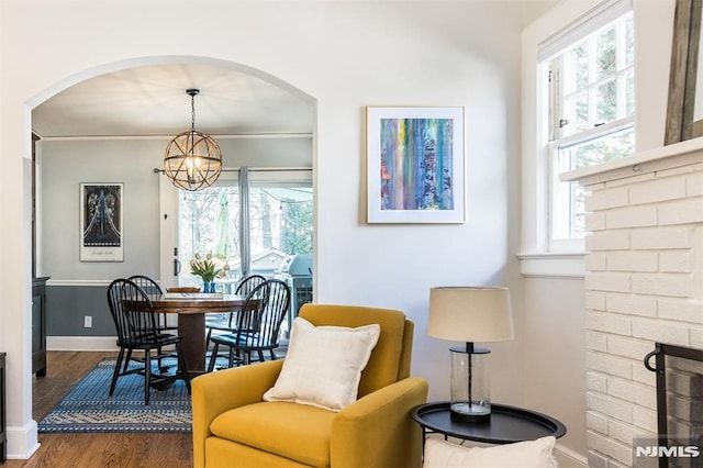 living area featuring a chandelier, a healthy amount of sunlight, wood finished floors, and a fireplace