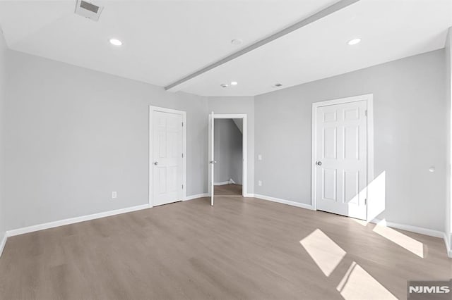 unfurnished bedroom featuring wood finished floors, visible vents, and baseboards