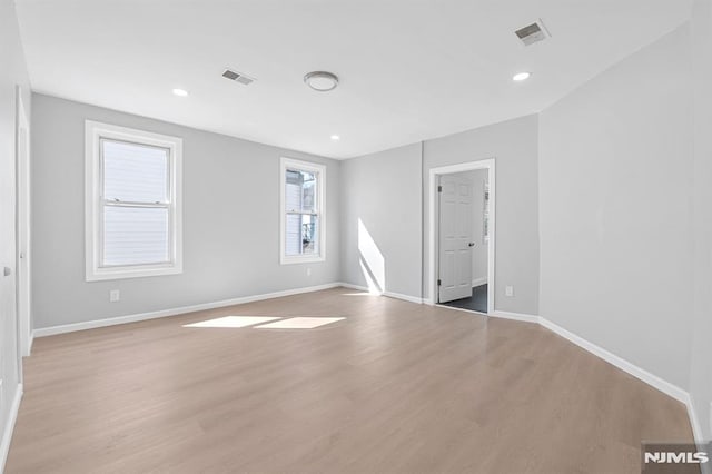 spare room with baseboards, visible vents, and light wood finished floors