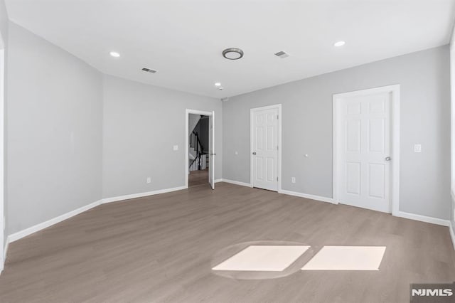 empty room featuring visible vents, recessed lighting, baseboards, and wood finished floors