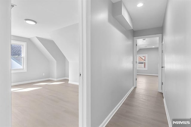 hall with vaulted ceiling, baseboards, and wood finished floors