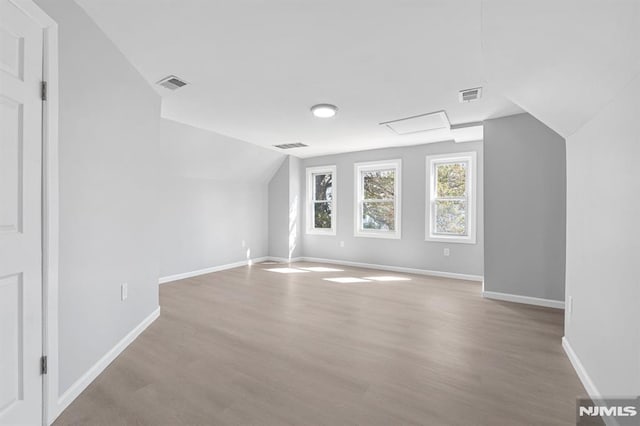 bonus room featuring vaulted ceiling, wood finished floors, visible vents, and baseboards