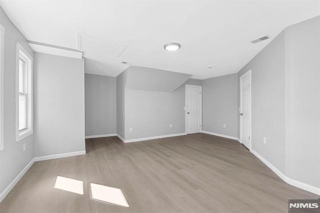 interior space featuring visible vents, attic access, baseboards, and wood finished floors