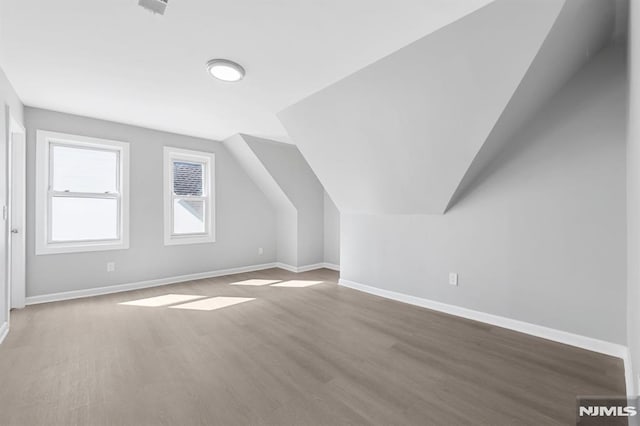 bonus room featuring baseboards, lofted ceiling, and wood finished floors