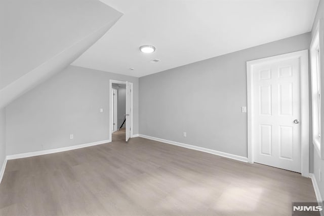 bonus room with baseboards, wood finished floors, and vaulted ceiling