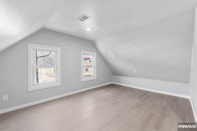 bonus room with wood finished floors, plenty of natural light, baseboards, and visible vents