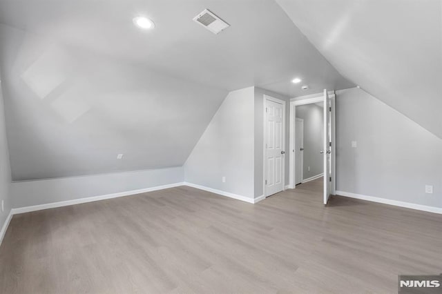 additional living space with visible vents, lofted ceiling, baseboards, and wood finished floors