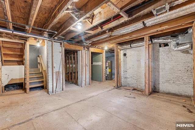 unfinished below grade area with stairs, brick wall, and water heater