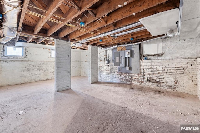 basement featuring electric panel and brick wall