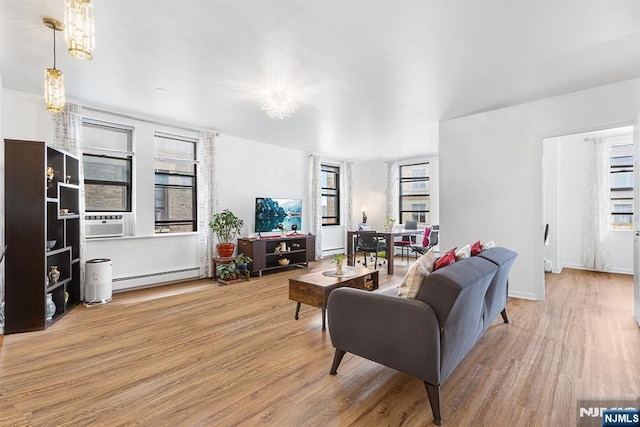 living area featuring cooling unit, baseboard heating, an inviting chandelier, and wood finished floors