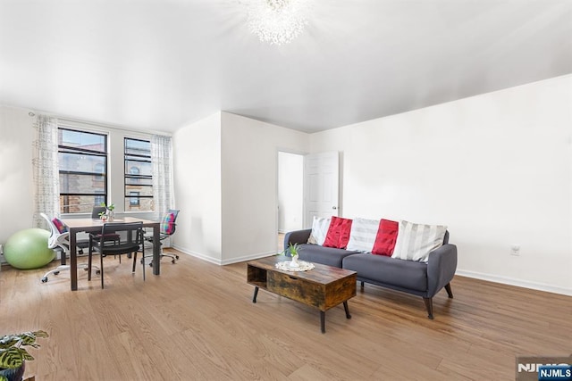 living area featuring baseboards, light wood-style floors, and an inviting chandelier