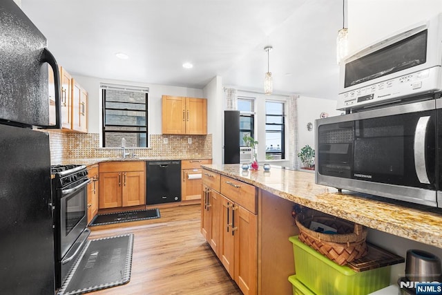 kitchen with pendant lighting, black appliances, light wood-style flooring, decorative backsplash, and light stone countertops