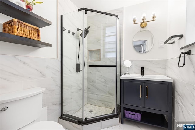 bathroom with vanity, a shower stall, tile walls, toilet, and marble finish floor