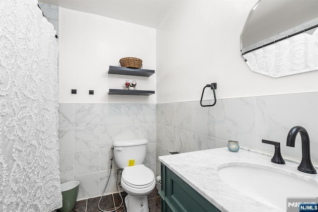 bathroom with tile walls, a wainscoted wall, toilet, tile patterned floors, and vanity