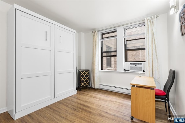 office area featuring cooling unit, baseboard heating, and wood finished floors