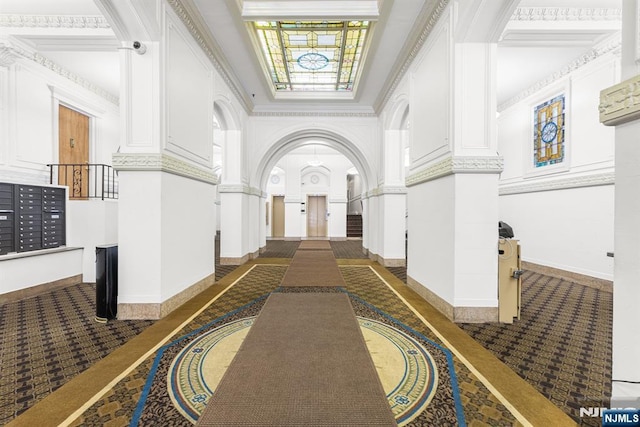 corridor with decorative columns, arched walkways, baseboards, and dark colored carpet