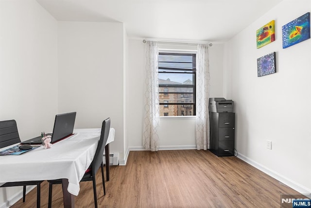 office space featuring a baseboard heating unit, baseboards, and wood finished floors