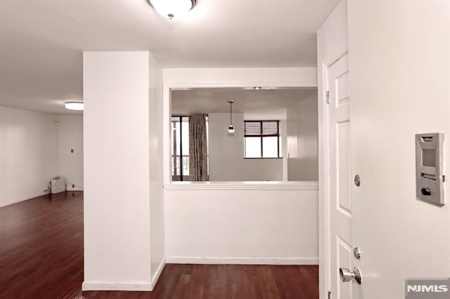 hall with baseboards and wood finished floors