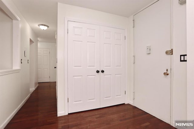 hallway with baseboards and dark wood-style flooring