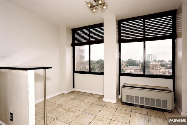 tiled empty room with radiator and baseboards