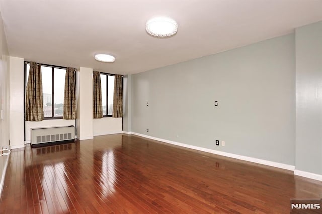 spare room with radiator, baseboards, and hardwood / wood-style floors