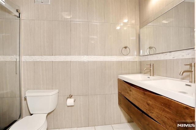 bathroom featuring double vanity, toilet, and tile walls