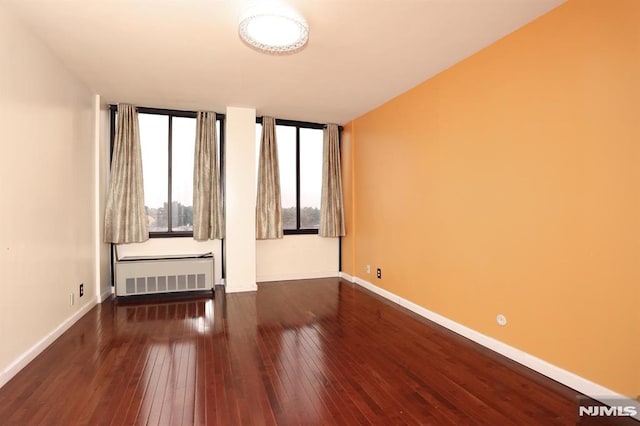 spare room featuring hardwood / wood-style floors, radiator heating unit, and baseboards