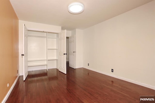 unfurnished bedroom featuring a closet, baseboards, and dark wood finished floors