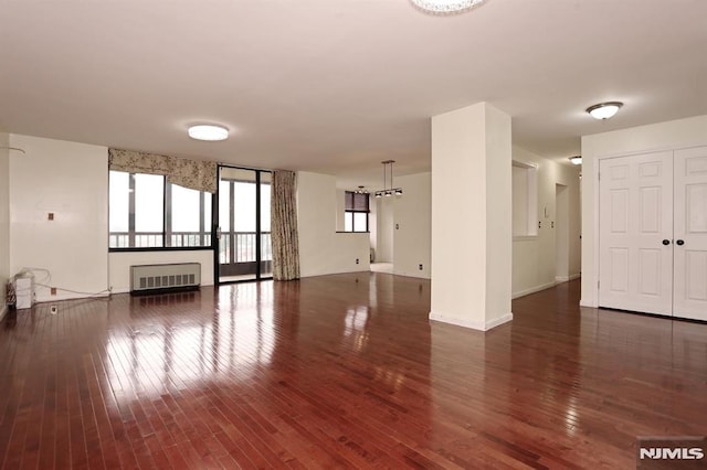 unfurnished room with radiator heating unit, baseboards, and wood-type flooring