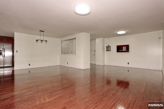 unfurnished room with baseboards and dark wood-style flooring