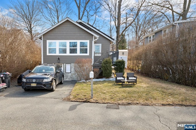 view of front of home with a front lawn, stone siding, and driveway