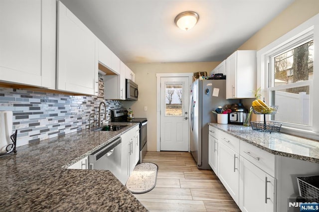 kitchen featuring a sink, stainless steel appliances, tasteful backsplash, and white cabinets