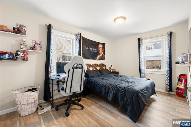 bedroom with light wood finished floors, multiple windows, and baseboards