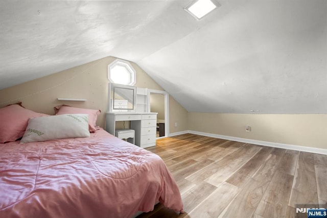 bedroom with baseboards, lofted ceiling, and light wood-style floors