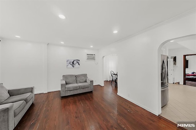 living room with a wall mounted AC, wood finished floors, recessed lighting, arched walkways, and crown molding