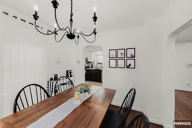 dining room with arched walkways, a notable chandelier, baseboards, and ornamental molding