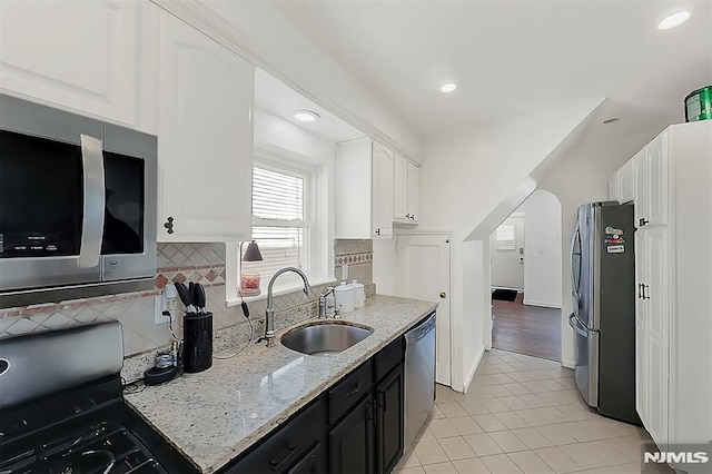 kitchen with a sink, light stone countertops, white cabinetry, and stainless steel appliances